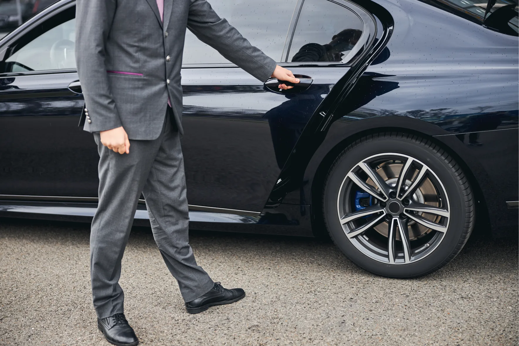 a man in a suit and tie walking towards a car
